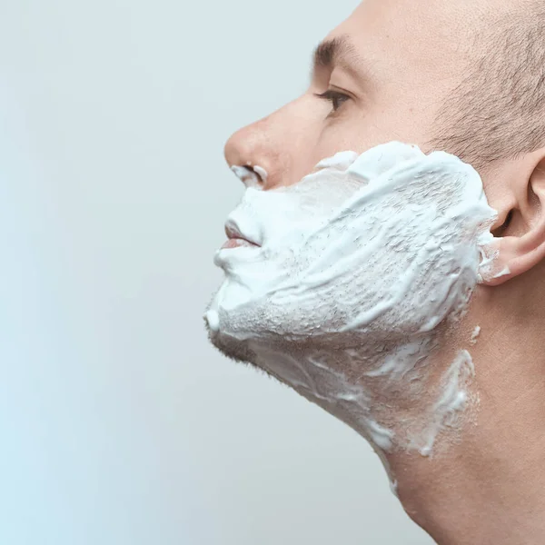 Primer plano retrato de la cara del hombre en espuma de afeitar sobre fondo gris. —  Fotos de Stock