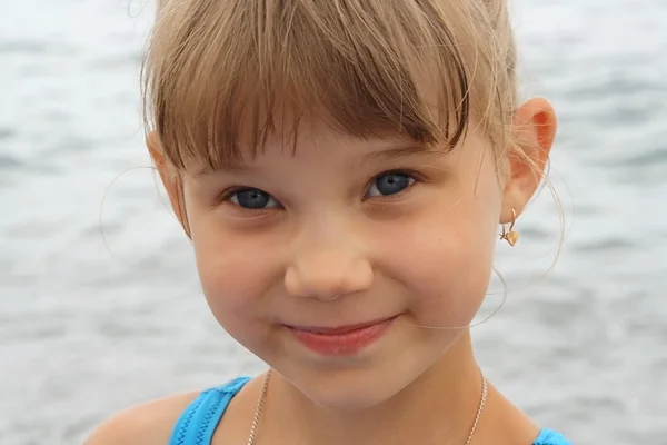 Sourire bébé fille aux yeux bleus sur fond de mer — Photo