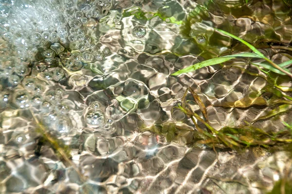 Fondo de guijarros visto a través del agua ondulante — Foto de Stock