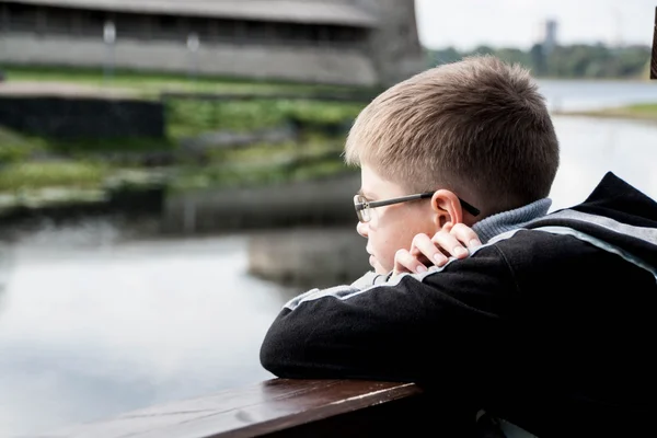 Сумний хлопчик дивиться на річку — стокове фото