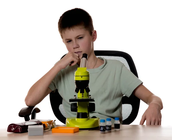 Menino adolescente pensando como fazer a experiência sobre microscópio — Fotografia de Stock