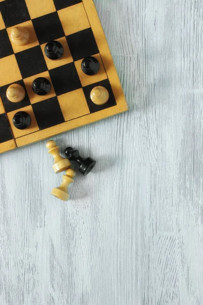 Gri ahşap arka plan üzerinde siyah beyaz piyon ile eski kırpılmış satranç tahtası. Üstten Görünüm. Düz yatıyordu.