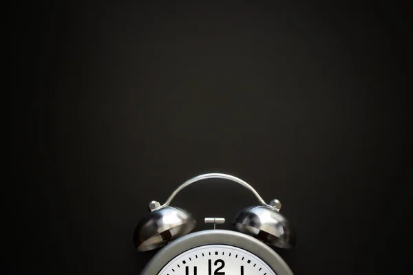 Reloj despertador clásico con campanas y flechas en el fondo de pizarra negra. Vista superior. De cerca. Acostado. Burla. —  Fotos de Stock
