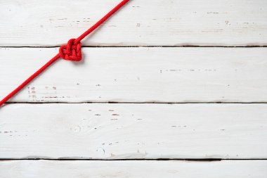Beyaz ahşap arka planda kalp şeklinde kırmızı bir ip. Düz yatıyordu. Aziz Sevgililer Günü hediye kartı için model.