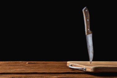 Masadaki tahta kesme tahtasına saplanmış eski bir metal bıçak. Yatay görüş. Metin için kopyalama alanı olan siyah arkaplanda izole edilmiş. Model