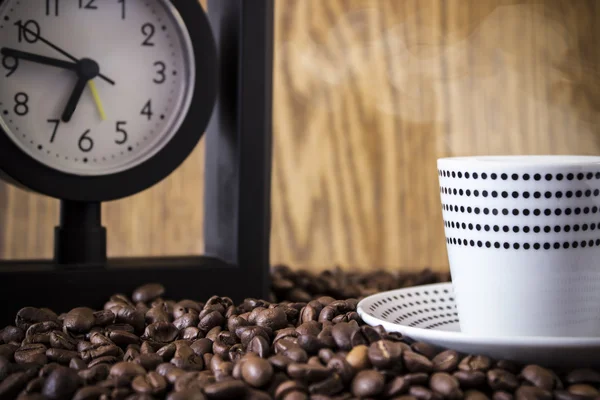 Kubek kropki i zegar stojący na ziarna kawy. Plama, o ostrości — Zdjęcie stockowe