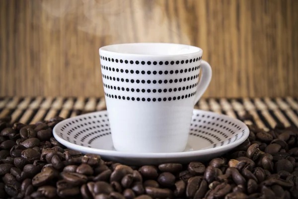 Tazza pois in piedi su chicchi di caffè. Sfocatura, concentrati sulla tazza. — Foto Stock