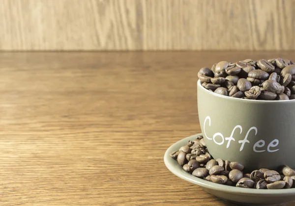 Eine Tasse Kaffee mit Bohnen steht auf einem Holztisch. Ernte, blu — Stockfoto