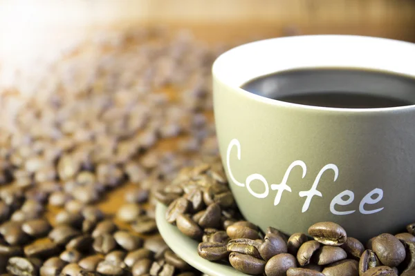 Eine Tasse Kaffee mit Bohnen steht auf einem Holztisch. Ernte, blu — Stockfoto