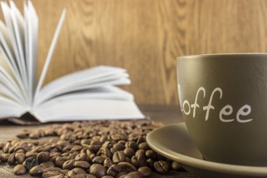 Kahve çekirdekleri önünde ile ahşap bir masa üzerinde duran kitap açın. Kırpma, bulanık, kupa odaklanmak