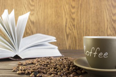 Kahve çekirdekleri önünde ile ahşap bir masa üzerinde duran kitap açın. Kırpma, bulanık, kupa odaklanmak