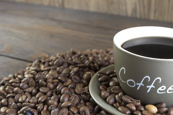 Eine Tasse Kaffee mit Bohnen steht auf einem Holztisch. Ernte, verschwommen, Fokus auf Becher — Stockfoto