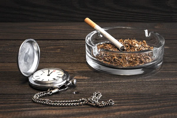 빈티지 포켓 시계와 오래 된 나무 테이블에서 유리 재떨이와 담배 — 스톡 사진