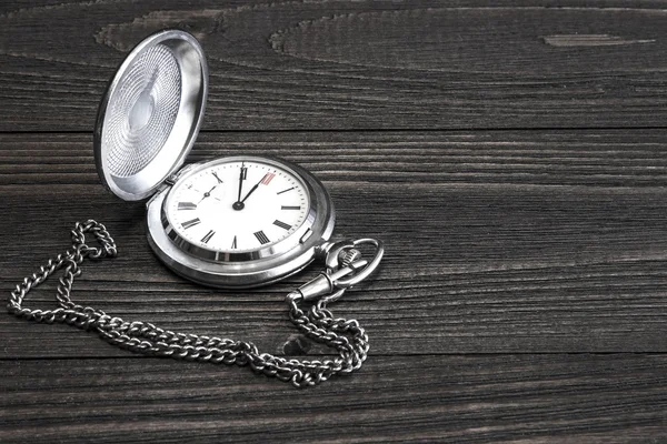 Old pocket watch with chain lying on a wooden table. Black and white photo. Focus on the dial — Stock Photo, Image