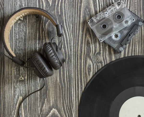 Müzik ekipman kulaklık ses kaseti ve plaka üzerinde ahşap bir masa yalan. Arka plan Üstten Görünüm