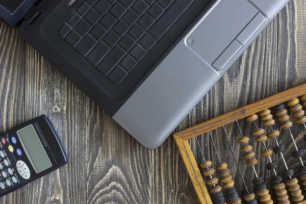 Notebook laptop faturaları ve tahta bir masanın üzerinde yatan hesap makinesi. Arka plan Üstten Görünüm
