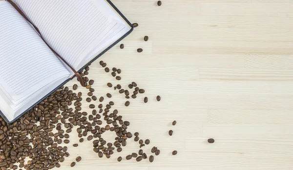 빈 메모장 그리고 나무 바탕에 엎지른된 커피 콩. 상위 뷰 — 스톡 사진