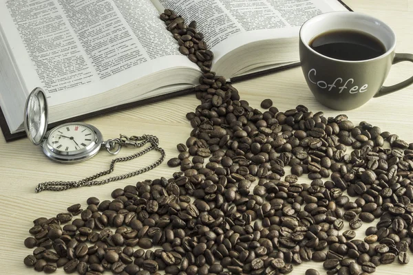 Das Buch, eine Tasse Kaffee, Kaffeebohnen und eine Taschenuhr auf einem Holztisch — Stockfoto