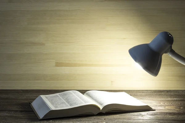 책은 어두운 방에 있는 테이블에 램프에서 빛에 의해 조명 — 스톡 사진