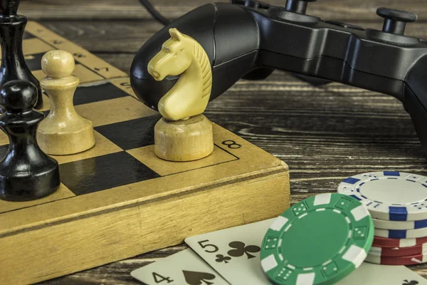 Gamepad, rakamları ile bir satranç tahtası ve iskambil ile masanın üzerindeki fişlere. Satranç at üzerinde odaklanmak