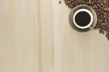 Bir fincan kahve kahve çekirdekleri ahşap bir masa üzerinde ile. 