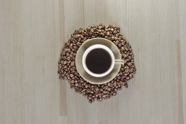 Bir fincan kahve kahve çekirdekleri ahşap bir masa üzerinde ile. 