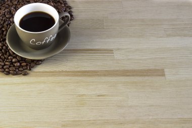 Bir fincan kahve kahve çekirdekleri ahşap bir masa üzerinde ile. 