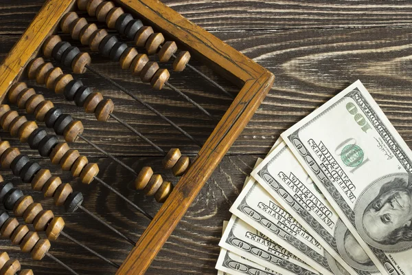 Eski ahşap abaküs ve tahta bir masanın üzerinde yatan bir kaç dolar faturaları. Üstten Görünüm