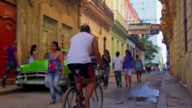 Etrafta dolaşan insanlar ile Habana Vieja bölgesinde eski model yeşil araba park