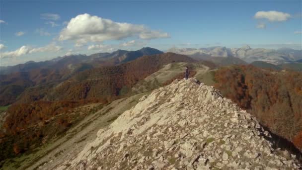 Vue aérienne d'une femme au sommet d'une montagne rocheuse volant de loin à proximité Clip Vidéo