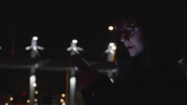 Kadın bir akıllı telefon gece şehirde kullanır
