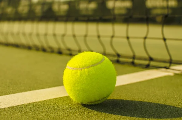 Tennis Ball on the Court with the Net in the background — Stock Photo, Image