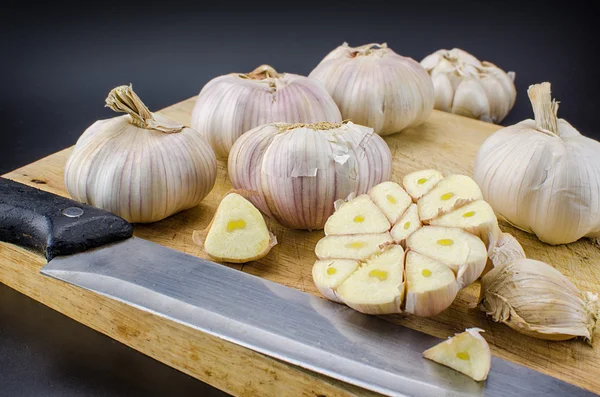 Zwiebeln von frischem Knoblauch mit mehreren Nelken auf dem Schneidebrett. — Stockfoto