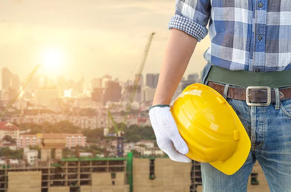 Homem segurando capacete amarelo — Fotografia de Stock