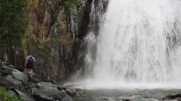 El hombre al pie de la cascada — Vídeo de stock