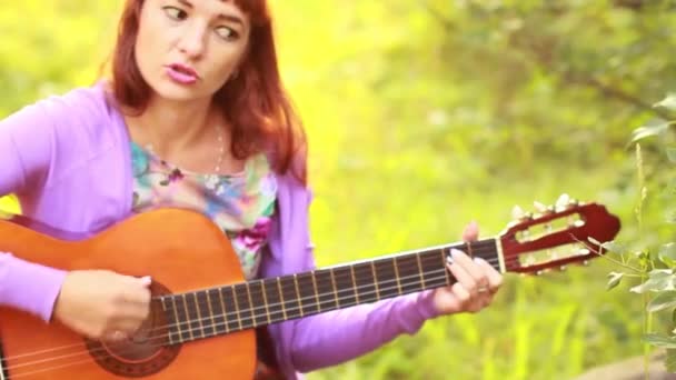 Красивая рыжая девушка, играющая на гитаре — стоковое видео