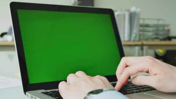 Empresario escribiendo en el ordenador portátil con pantalla verde en la mesa de cristal en la oficina — Vídeos de Stock