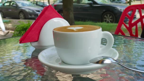 Una taza de café sobre una mesa de cristal — Vídeo de stock