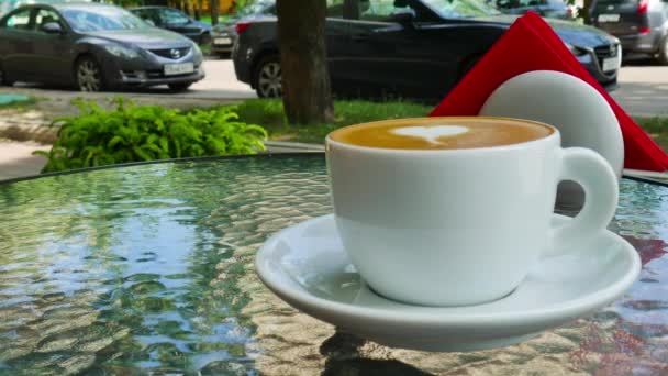 Una taza de café en una mesa de cristal en la terraza — Vídeo de stock