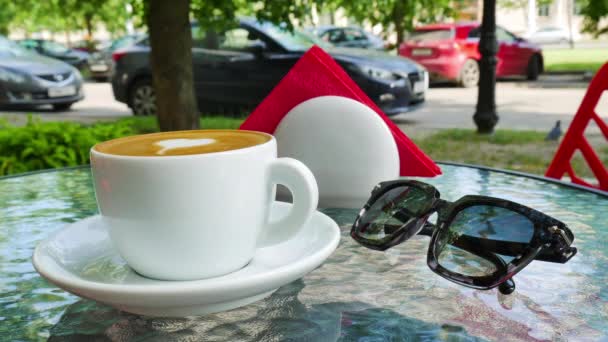 Uma chávena de café branca. Os óculos estão nas proximidades do copo Filmagem De Bancos De Imagens Sem Royalties