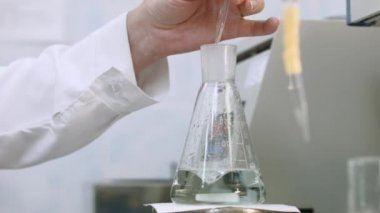 Resercher incelenmesi ve örnek yeşil sıvı şişesi içinde karıştırın