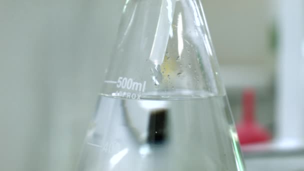 Waterdruppel aan kolf in lab — Stockvideo