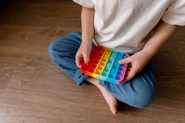 Küçük beyaz bir çocuk pop it sensör oyuncağı çalıyor. Sakin, sakin, anaokulu çocuğu. 