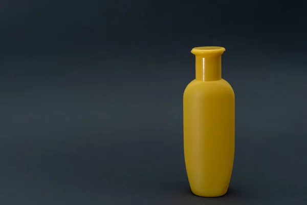Желтая бутылка жидкости на сером фоне — стоковое фото