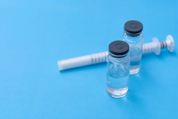 Szczepionka na szklanej butelce na niebieskim tle — Zdjęcie stockowe