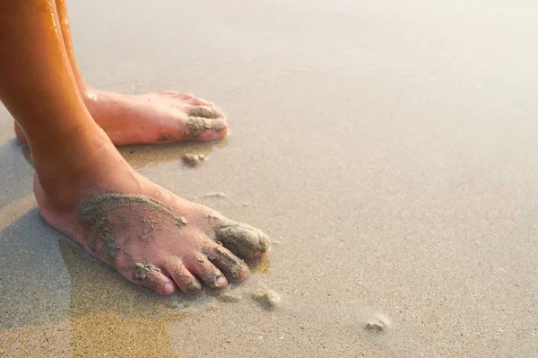 Voeten van een kind aan het zandstrand — Stockfoto