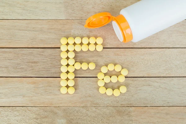 Sarı şekillendirme ahşap arka plan Fe alfabesine şekle hap