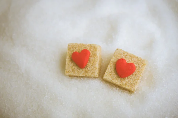 Brown sugar cube decorated  by little red heart  on  white sugar — Stock Photo, Image