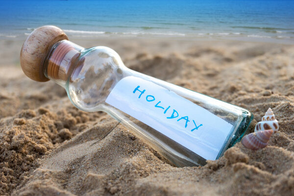 Message in glass bottle on sand with seascape background