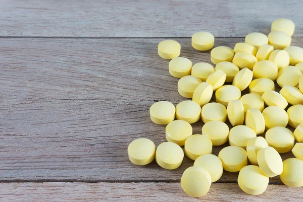 Pílulas amarelas em fundo de madeira com espaço de cópia — Fotografia de Stock